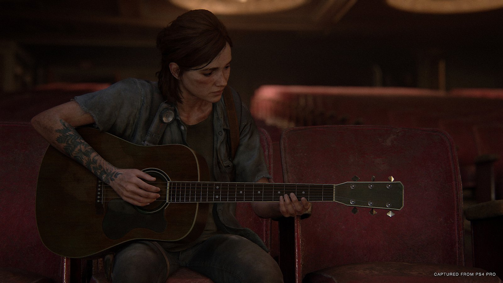 Ellie memainkan gitar dalam tangkapan layar The Last of Us Part II